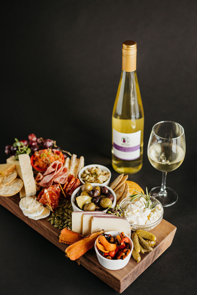 close up of a charcuterie board with a wine glass and a Nostrano Riesling wine bottle 